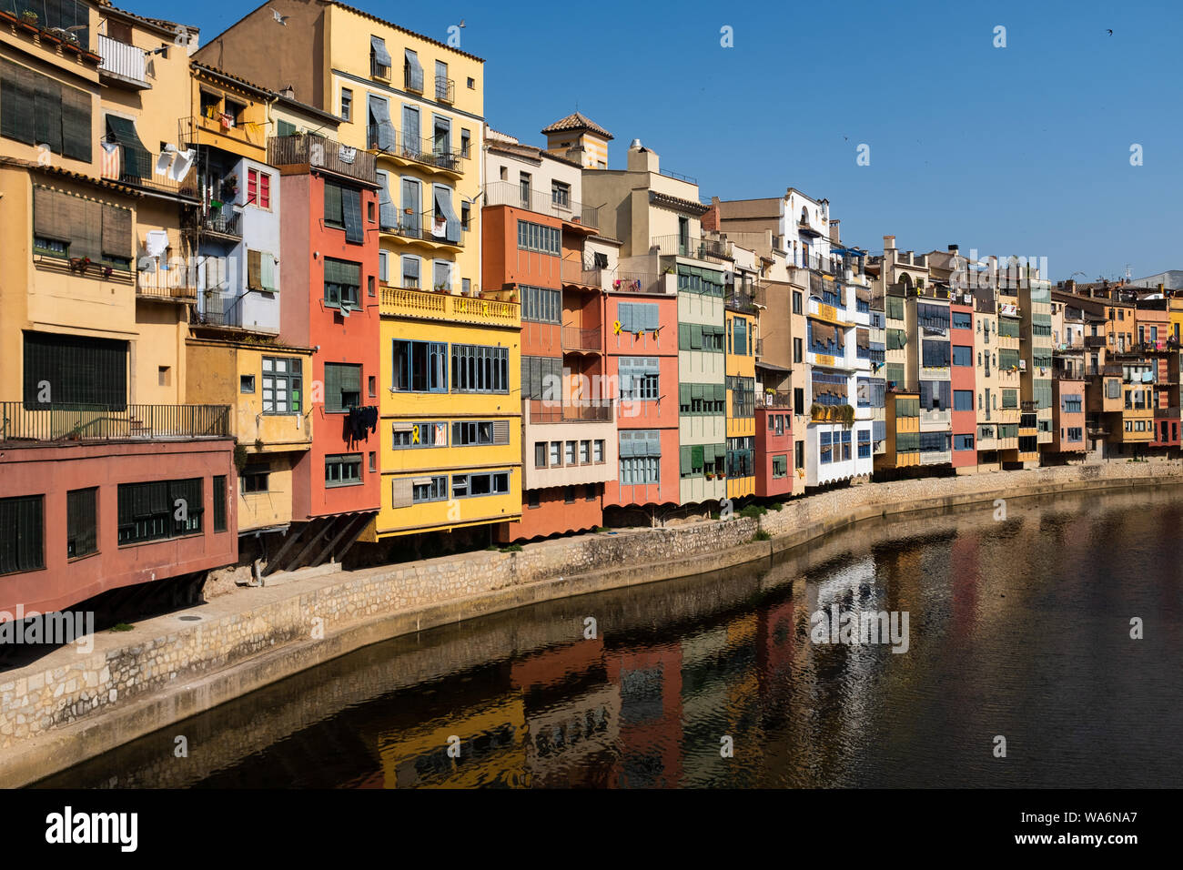 Gerona, Catalonia, Spain: multicolored houses in the old town with their charming reflections in the Onyar River. Panoramic photography taken from Gom Stock Photo
