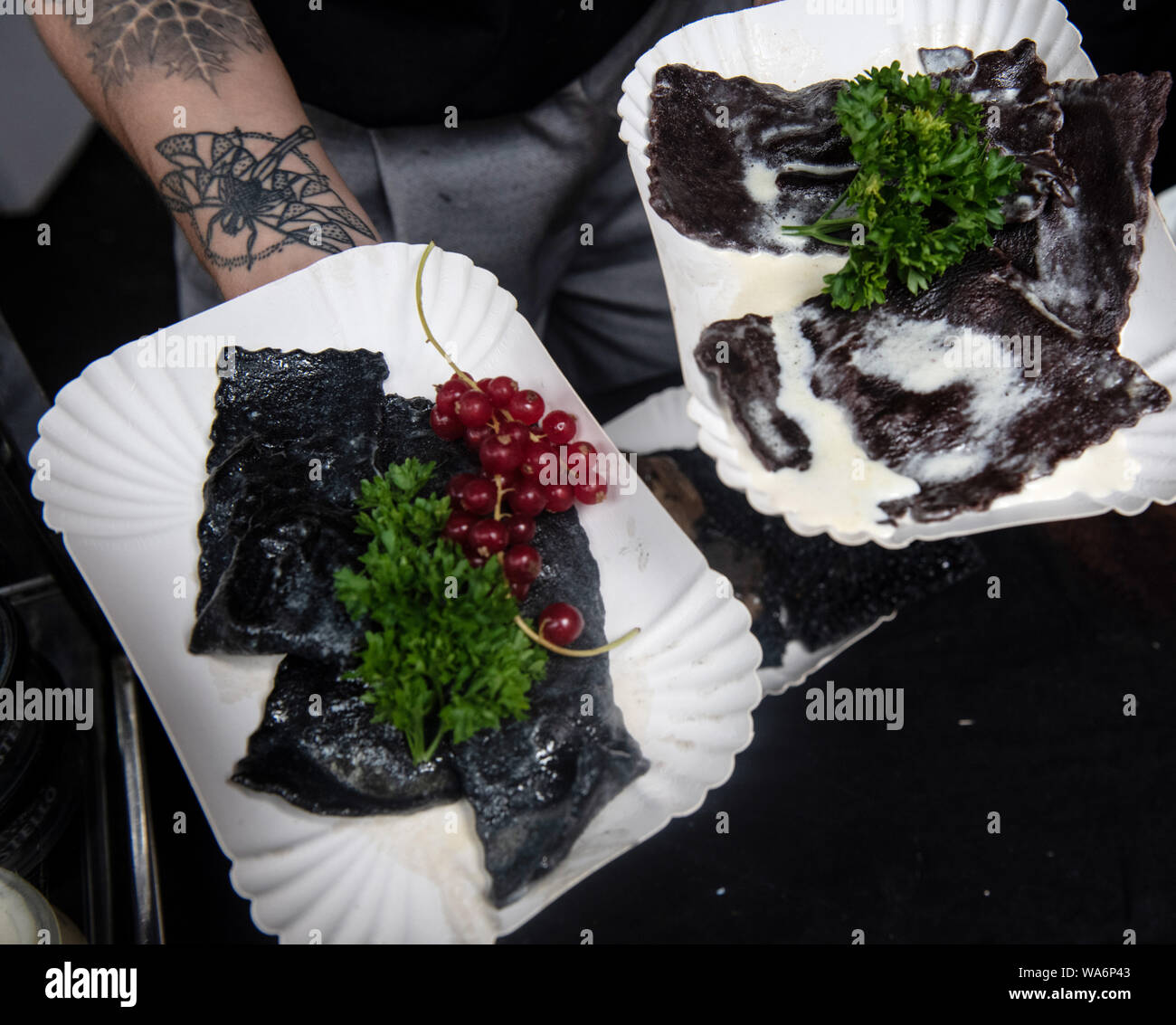 Berlin, Germany. 18 August 2019. A man shows black Maultaschen at the  