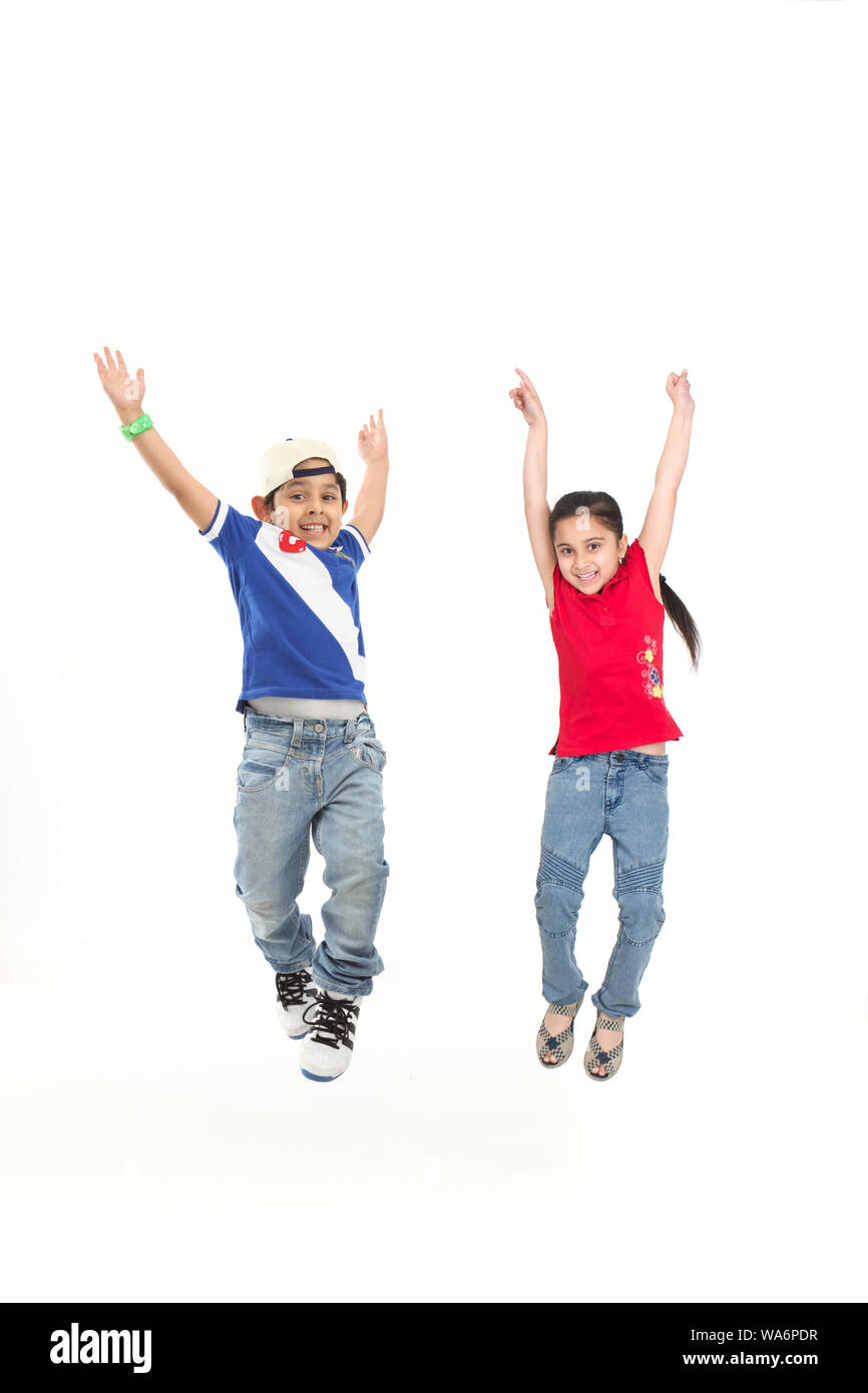 Two friends jumping in air with arm outstretched Stock Photo