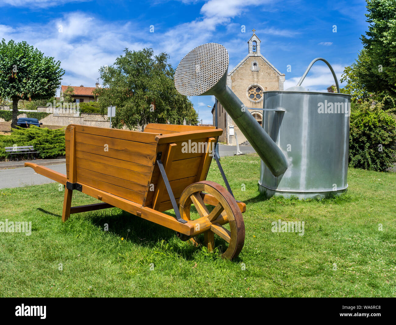 Large-scale watering can and wheelbarrow on display in 'book city' Montmorillon, Vienne, France. Stock Photo