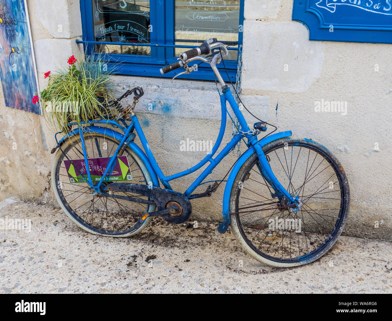 Old bicycle painted blue outside bookshop in 'book city' Montmorillon, Vienne, France. Stock Photo