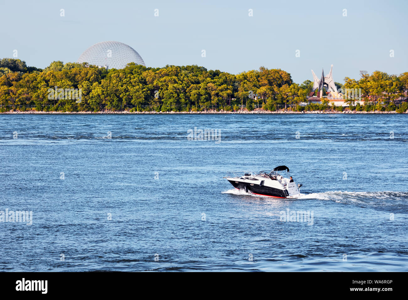 Motorboat sailing over the saint lawrence river with Saint Helen's island and biosphere in the background  in Montreal, Canada Stock Photo
