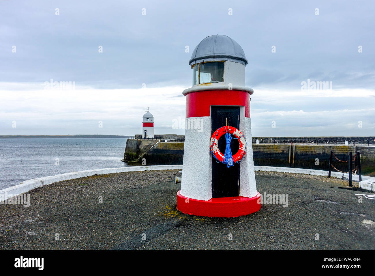 Red navigation beacons mark the Port (left) side of the entrance channel to Castletown Harbour, Isle of Man Stock Photo