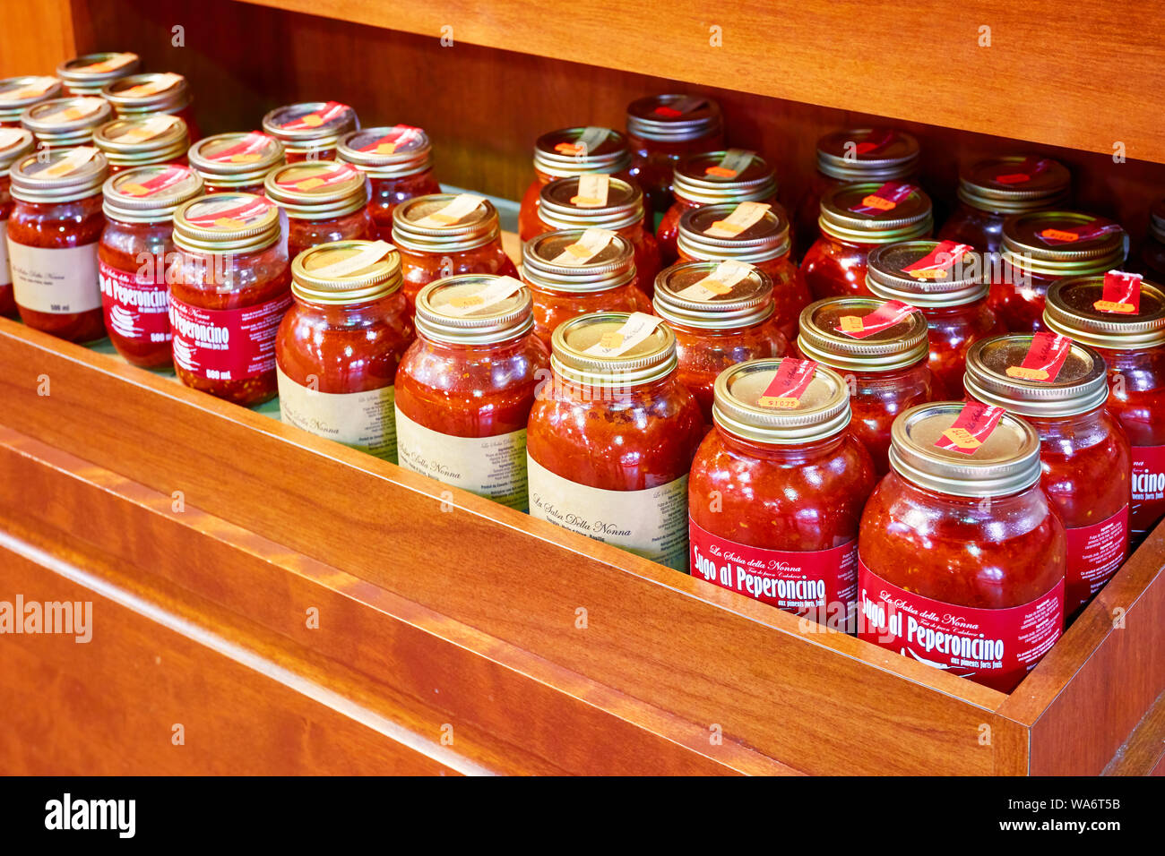 Tomato basil oil sauce and chili sauce jars on the wooden market shelf. Stock Photo