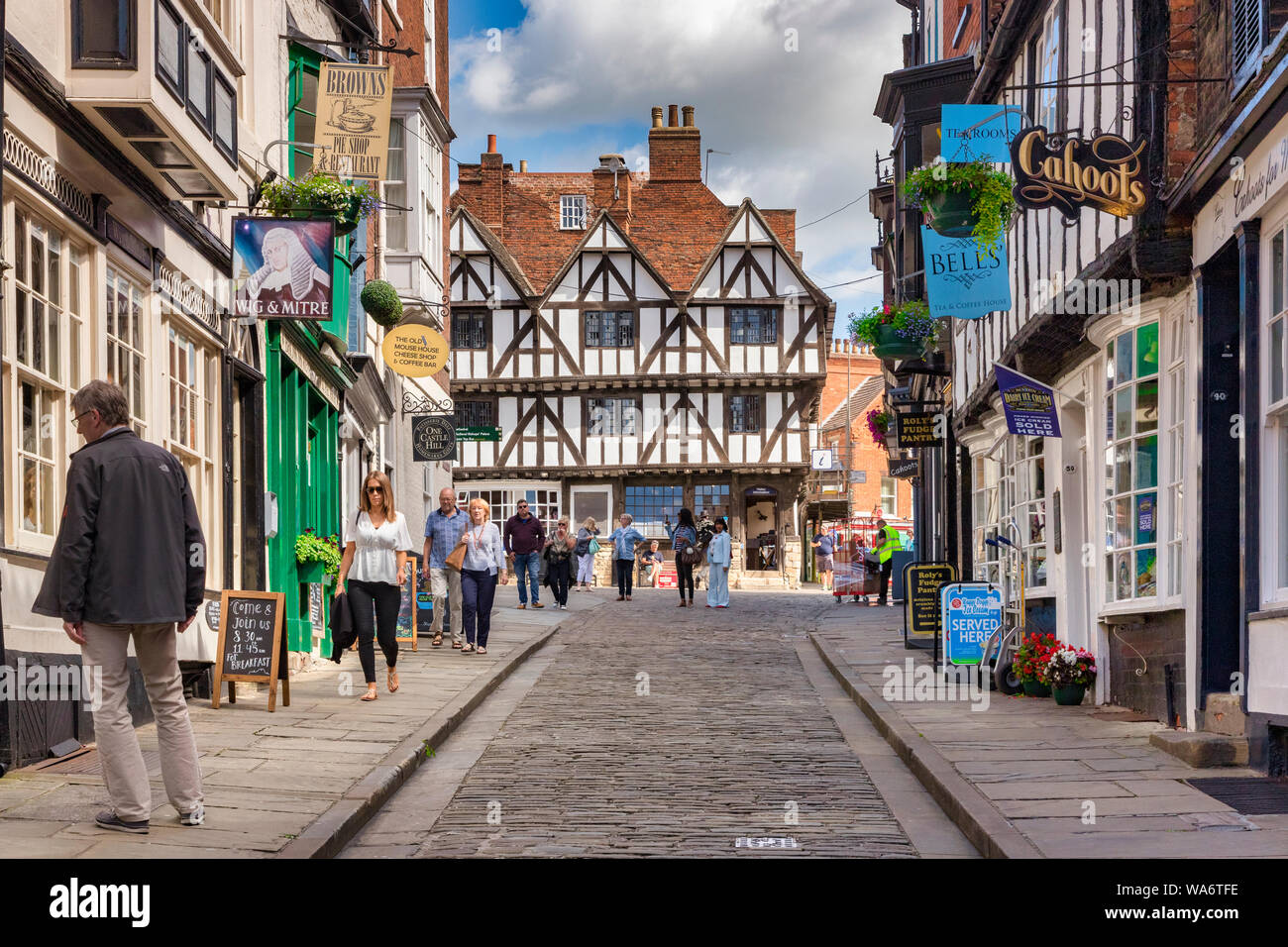 2 July 2019: Lincoln, UK - Tourists sightseeing in Steep Hill, the city's famous medieval street. The half timbered, black and white building at the t Stock Photo