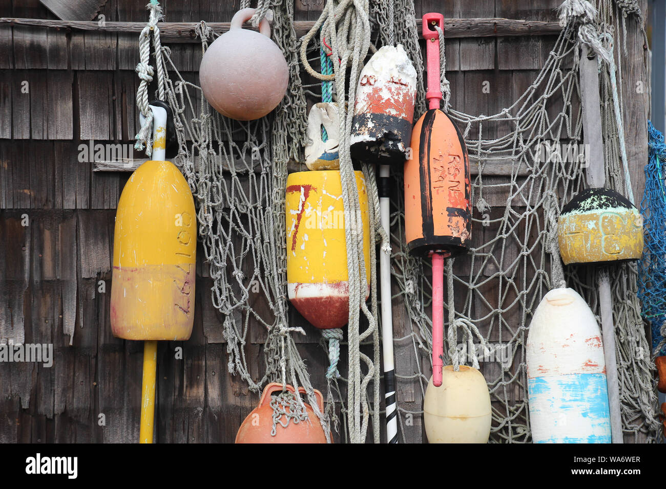 different types of colorful vibrant buoys hanging with netting on a  weathered wall Stock Photo - Alamy