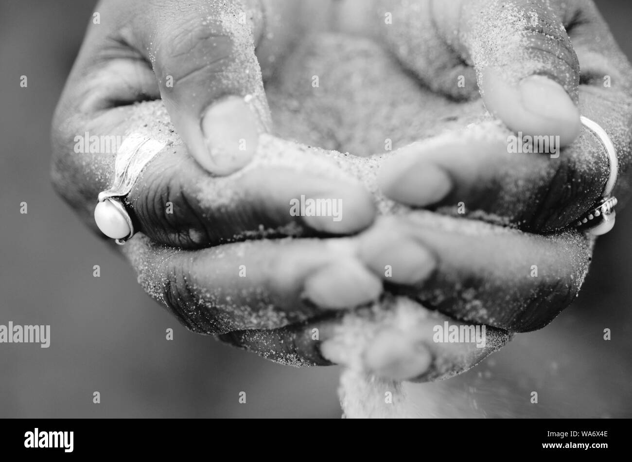 DNA Human: A man and woman squatting on Tybee beach have sand pouring through their hands. Stock Photo