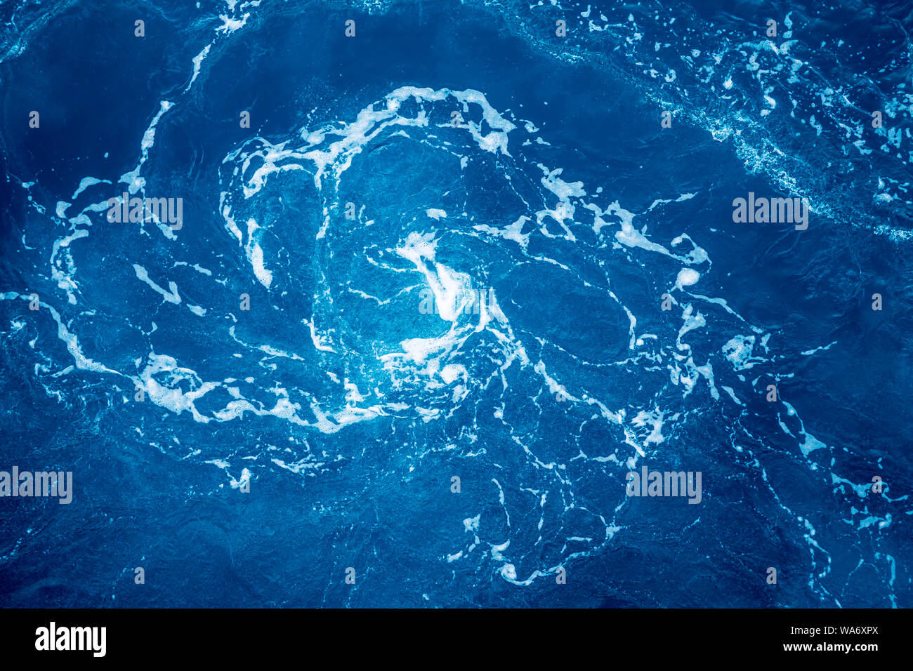 Vortex with foam in the ocean made by turning ship. Stock Photo