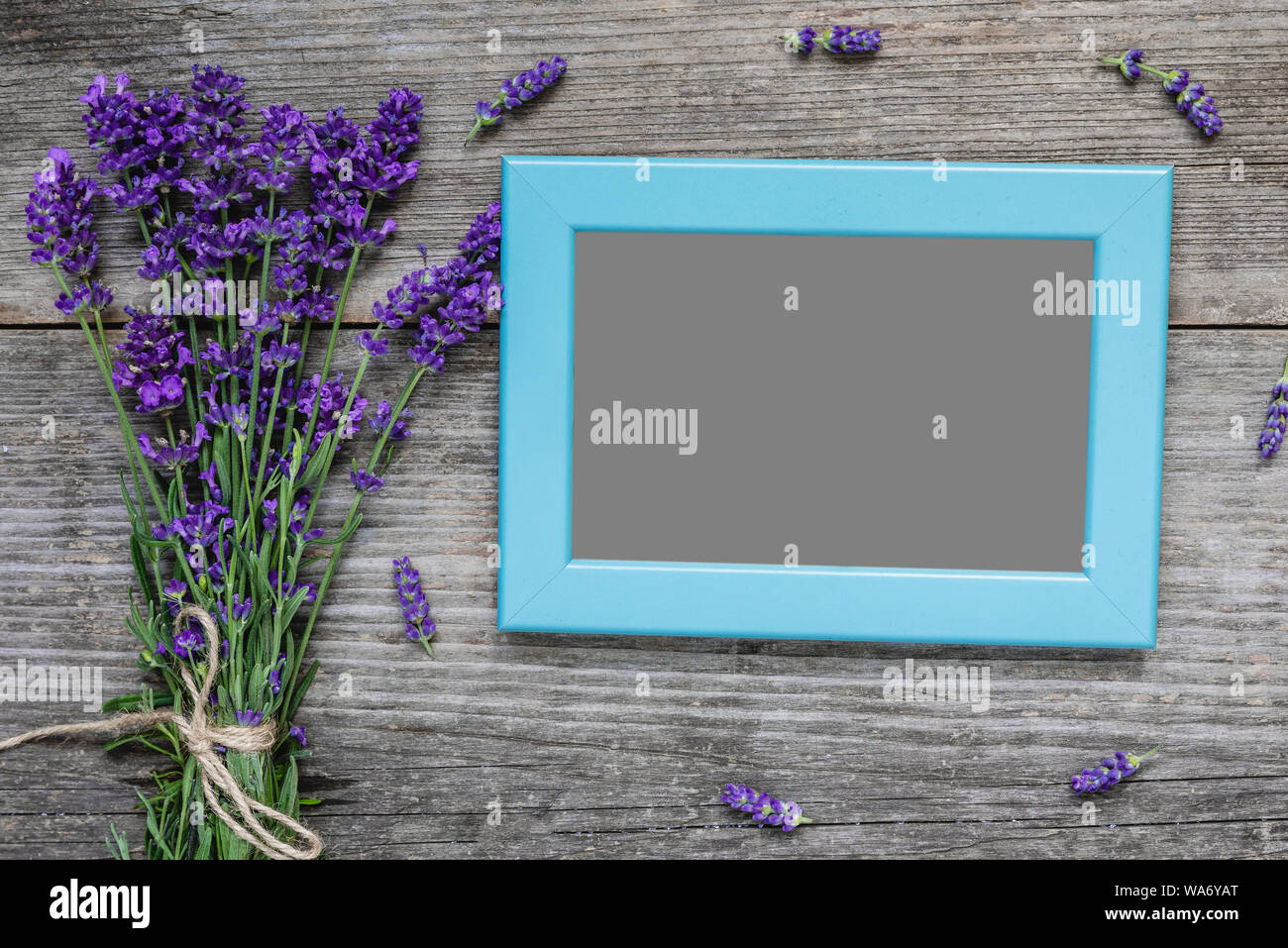 blank photo frame with lavender flowers bouquet on rustic wooden table. flat lay. mock up. festive or wedding background. top view Stock Photo