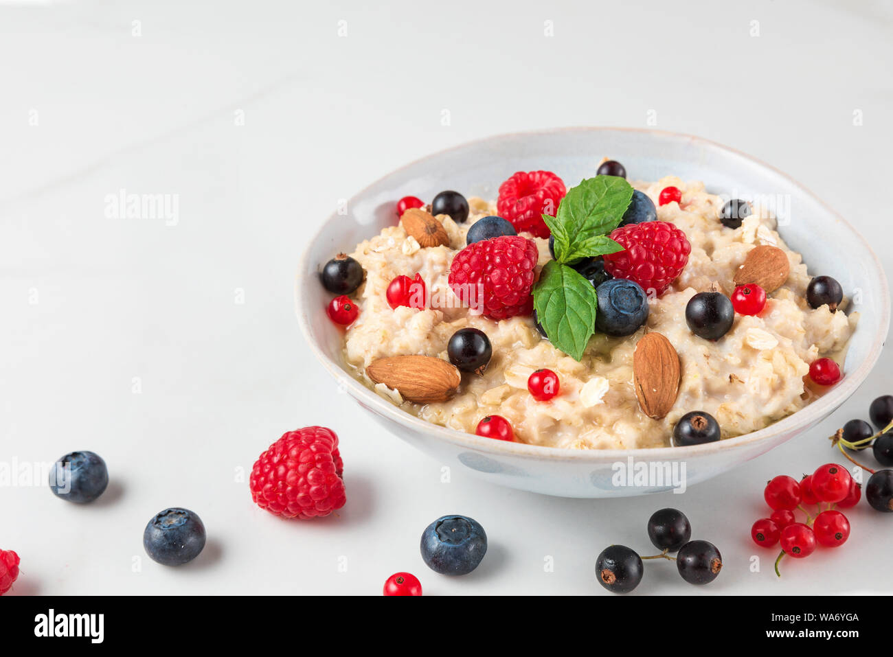 healthy homemade oatmeal porridge with berries, nuts and mint. diet