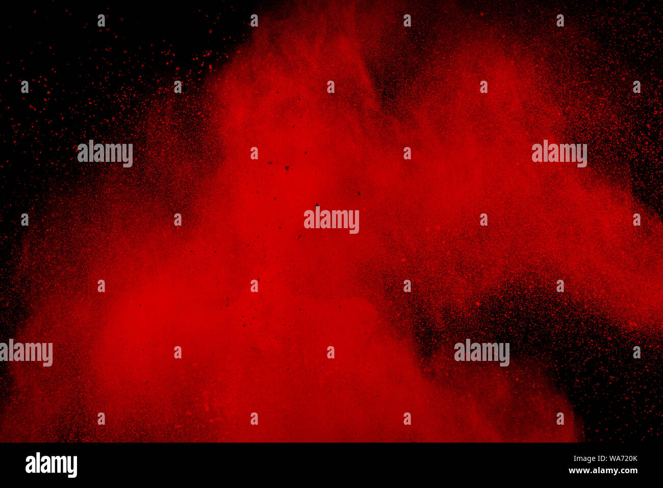 abstract red dust splattered on black background. Red powder explosion.Freeze motion of red particles splashing. Stock Photo
