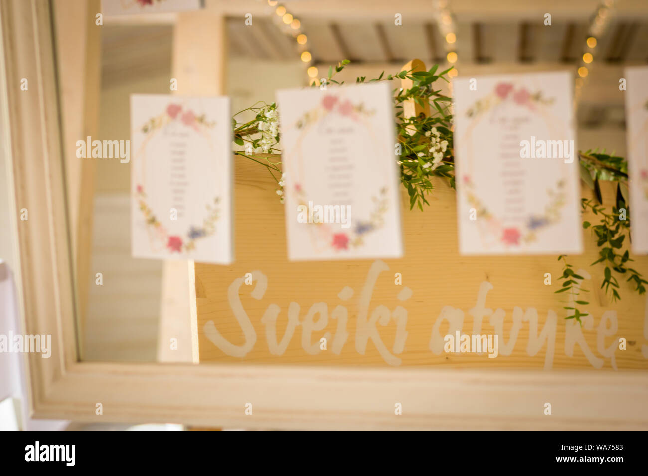 Wedding table sitting chart on cards attached to a mirror and reflection of green leaves Stock Photo