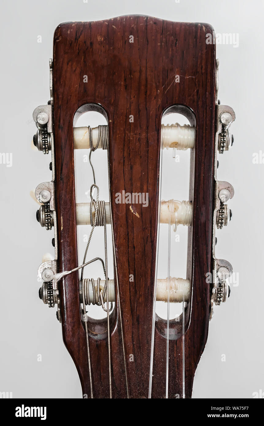 Headstock of an acoustic guitar, the head, the tuning pegs, capstans and strings. Details of an old acoustic guitar, worn out and dusty. Stock Photo