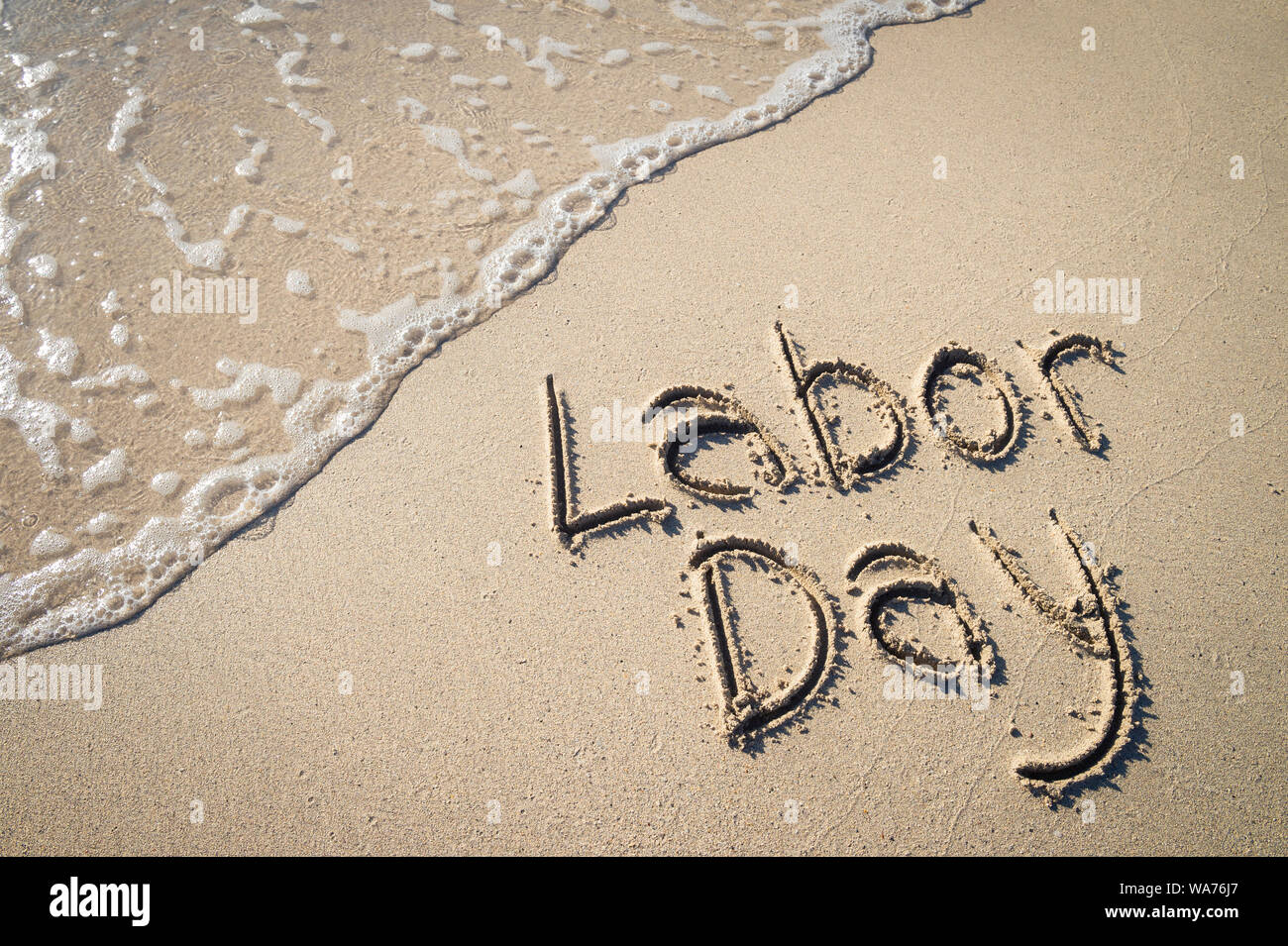 Labor Day message handwritten on the smooth sand of an empty beach with ...