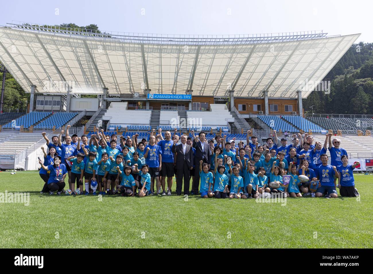 Kamaishi, Japan. 18 August 2019.  Takenori Noda Mayor of Kamaishi (C) alongside elementary-school children from Taiwan, Australia, Japan and organizers of the ''Kamaishi Kids Try'' sports event pose for the cameras at Kamaishi Unosumai Memorial Stadium. The ''Tohoku Media Tour: Iwate Course'' is organized by the Tokyo Metropolitan Government in collaboration with local authorities to showcase the recovery efforts in Tohoku area affected by the 2011 Great East Japan Earthquake and Tsunami. The Kamaishi Unosumai Memorial Stadium or Kamaishi Recovery Memorial Stadium will host the Fiji V Uruguay  Stock Photo