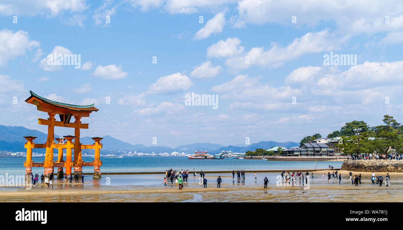 Japan, Miyajima. The Great Torii, or Otorii of the Itsukushima Shrine. Red Torii on sand with tide out and many people walking around it. Stock Photo