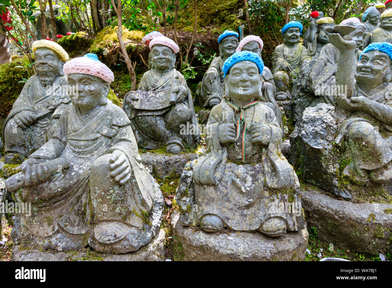 Japan, Miyajima. Small Rakan statues of Buddhist monks, disciples of Shaka, lining the stone step pathway by the entrance to the Daisho-in Temple. Stock Photo