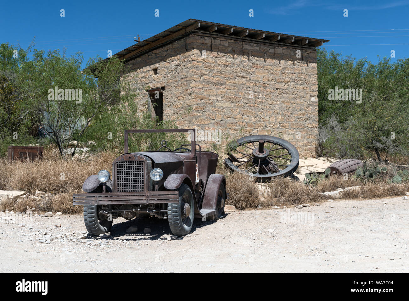 An old jalopy outside an abandoned stone building in the ghost town, some of which is still occupied and some of which consists of ruins of the Chisos quicksilver-mining company which operated from 1905 into the early 1940s, and the residences of those who worked there. Terlingua, Texas Stock Photo