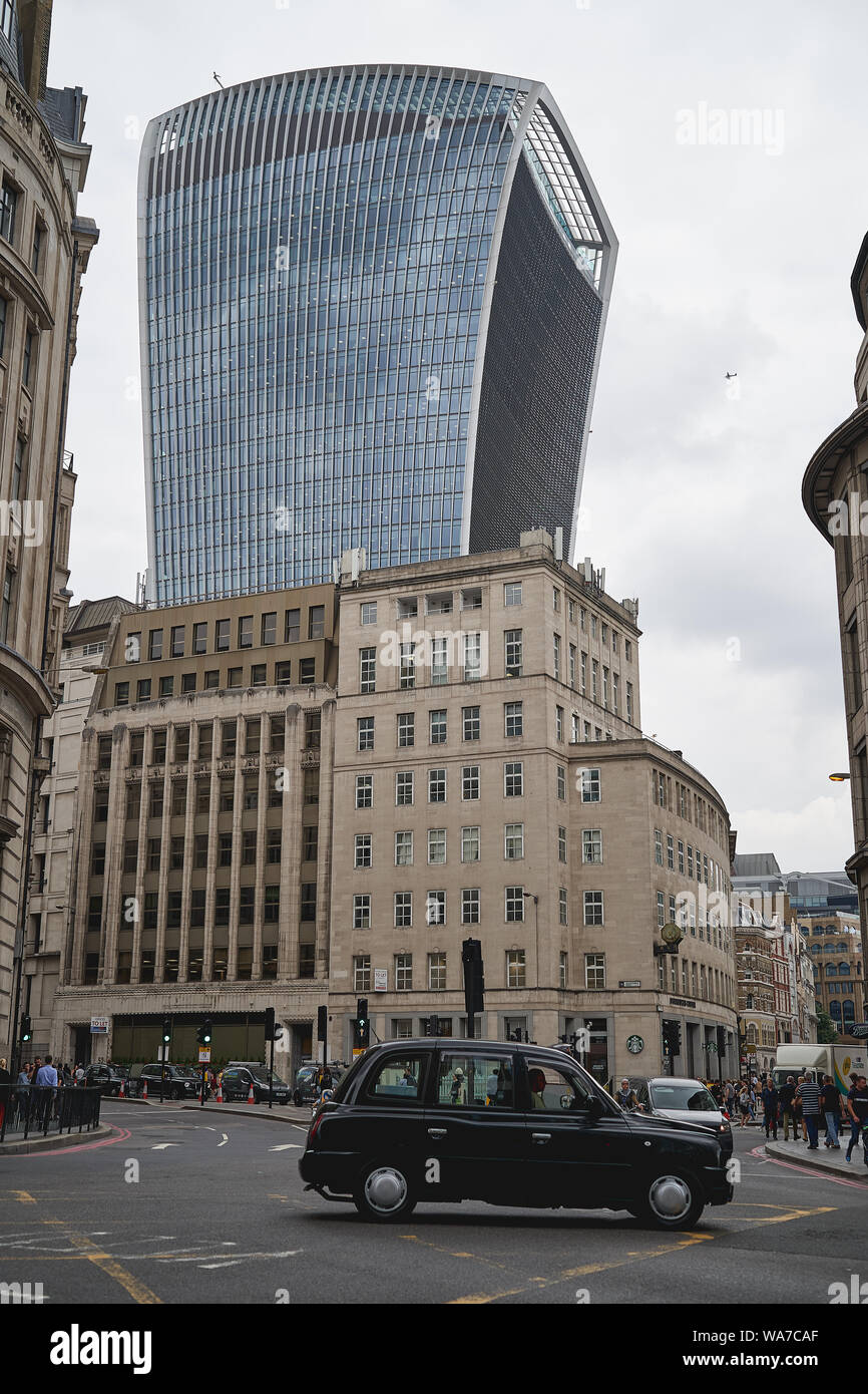 London, UK - August, 2019.  A typical black cab at a road junction in the City of London, financial district of London, with the famous Cheese Grater. Stock Photo