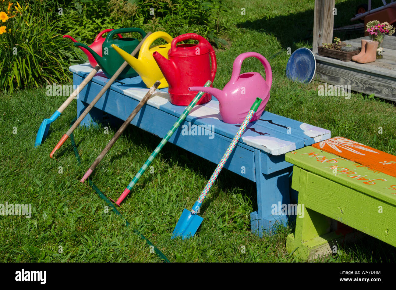 Colorful watering cans and shovels lined up for community garden learning summer camp for kids, Yarmouth, Maine, USA Stock Photo