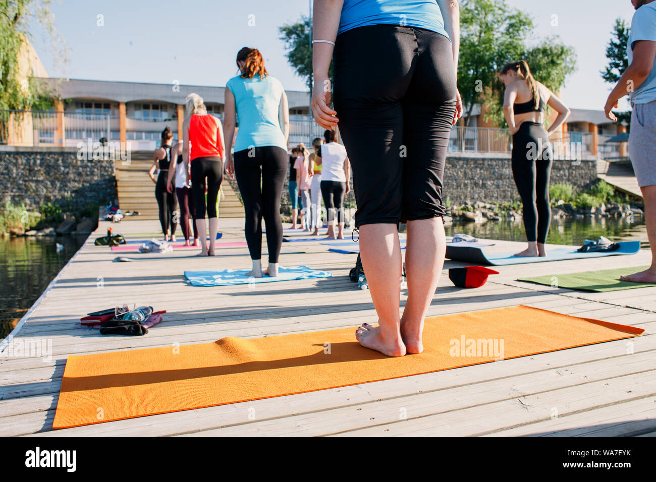 A big group of people attending yoga classes on a pontoon near the lake