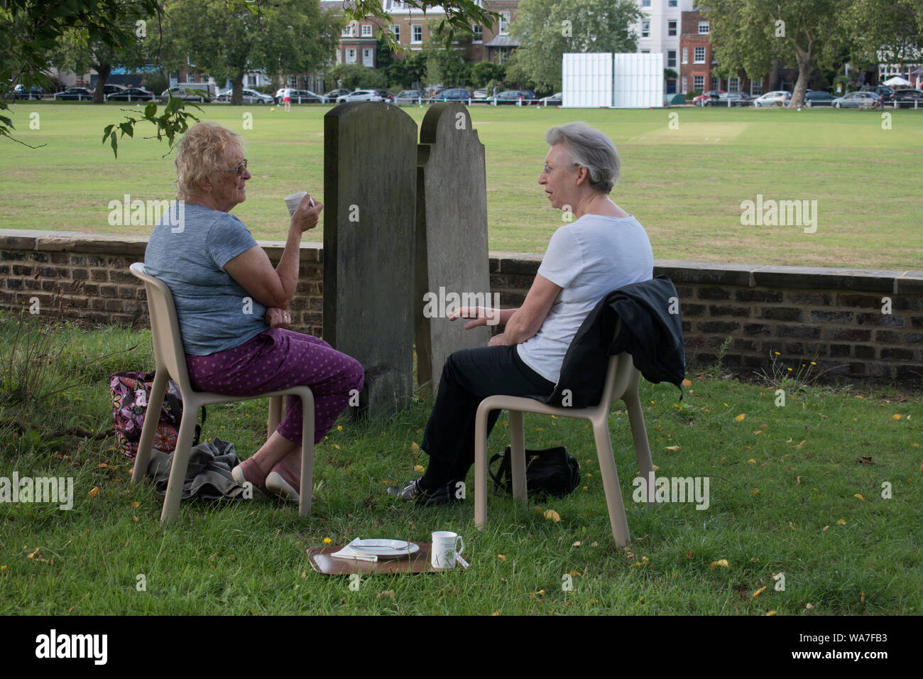 Afternoon tea UK  People two women friends catching up, chatting over a cup of English tea sitting in a church graveyard London 2010s HOMER SYKES Stock Photo
