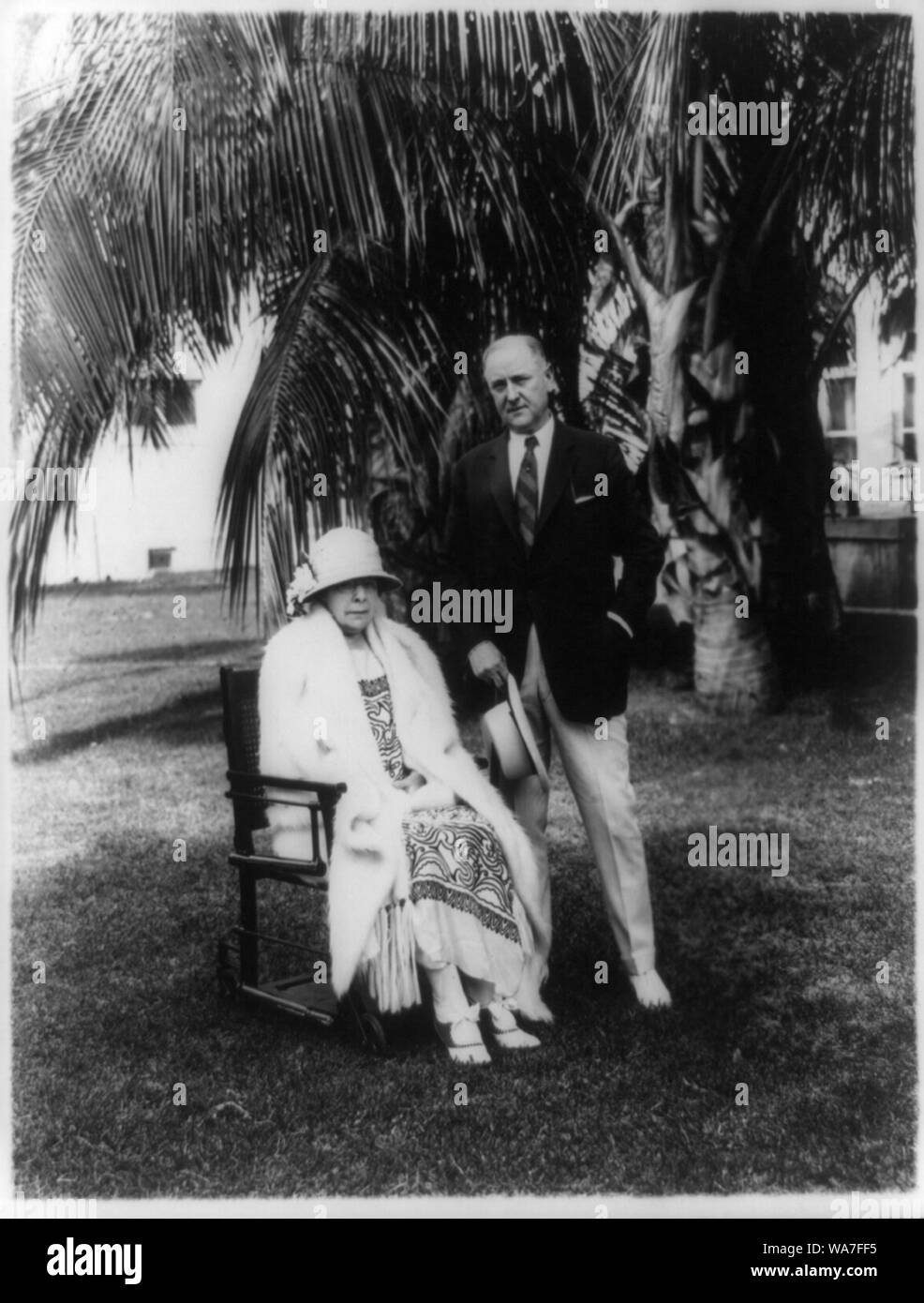 Atty. Gen. Harry Micajah Daugherty, full-length portrait, standing next to wife, under palm tree Stock Photo