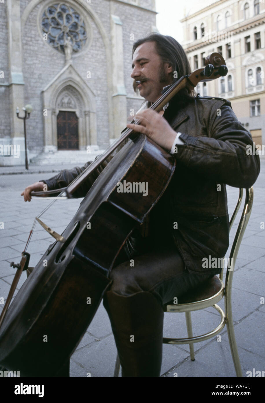 11th May 1993 During the Siege of Sarajevo: the 'cellist of Sarajevo', Vedran Smailović, performs in front of the Sacred Heart Cathedral. Stock Photo