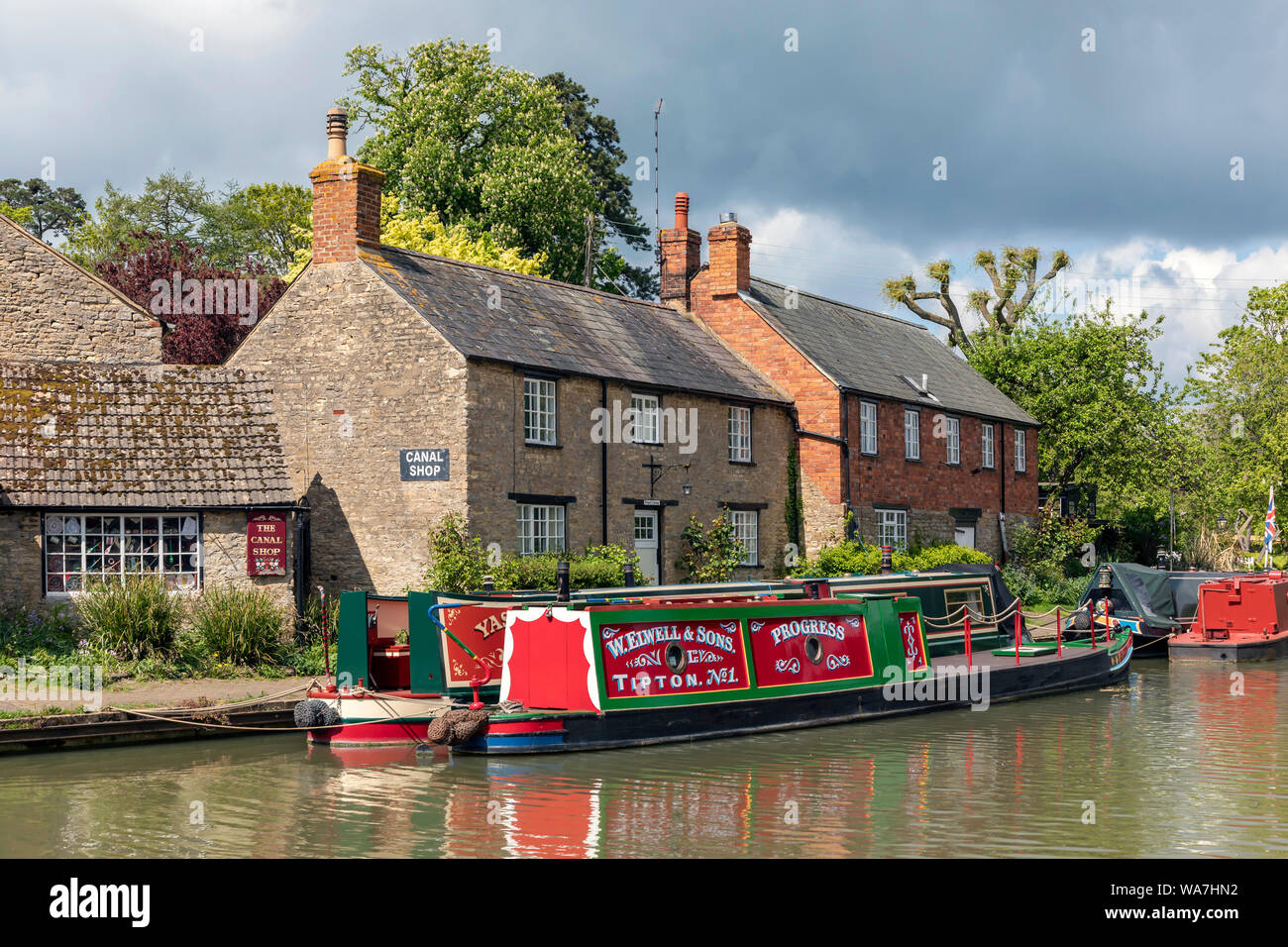 STOKE BRUERNE, NORTHAMPTONSHIRE, UK - MAY 10, 2019:   Narrowboats moored Grand Union Canal beside pretty cottages Stock Photo