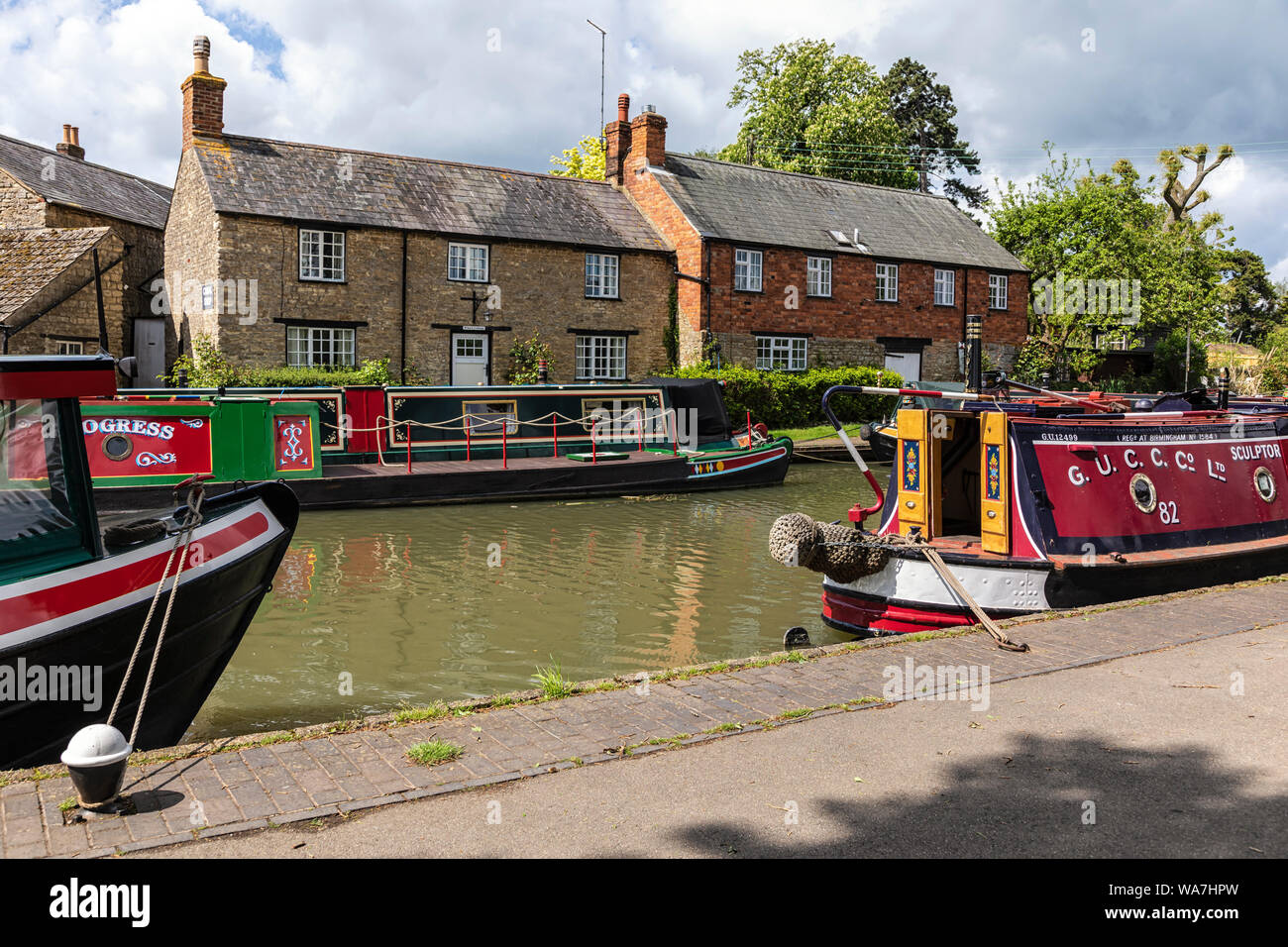 STOKE BRUERNE, NORTHAMPTONSHIRE, UK - MAY 10, 2019:  Narrowboats moored Grand Union Canal beside pretty cottages Stock Photo
