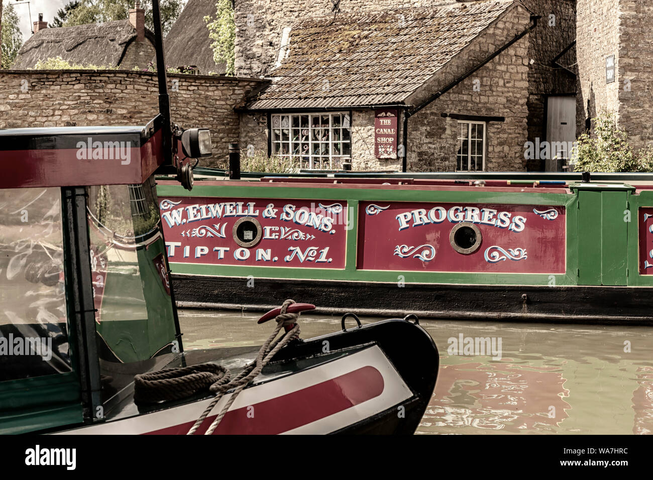 STOKE BRUERNE, NORTHAMPTONSHIRE, UK - MAY 10, 2019:  Narrowboats moored Grand Union Canal beside pretty buildings Stock Photo
