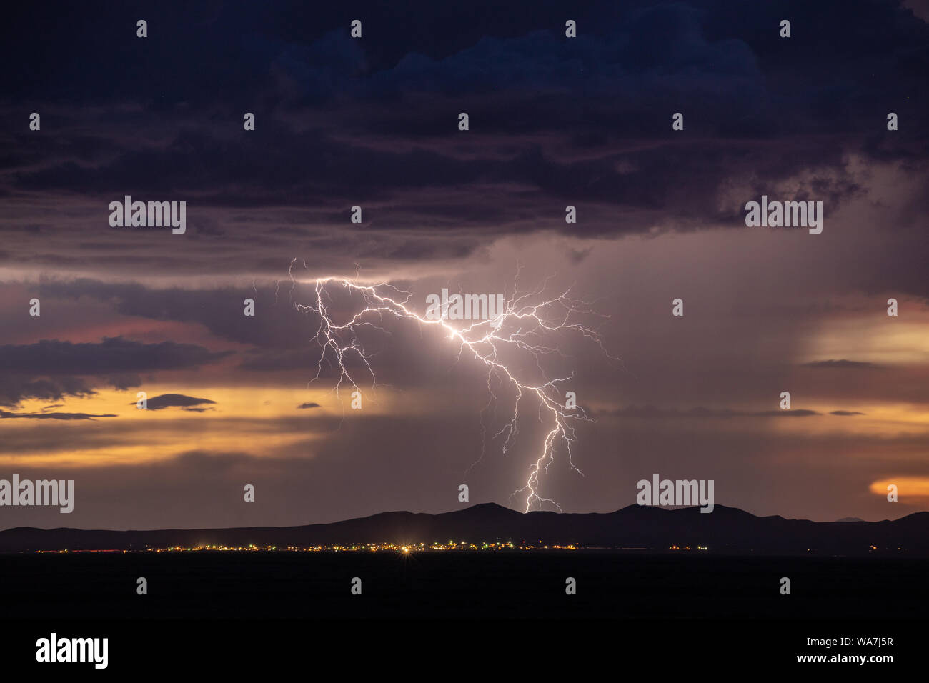 A cloud to ground lightning strike with multiple fine forks strikes behind distant mountains near Columbus, New Mexico, USA and Palomas, Chihuahua, Me Stock Photo