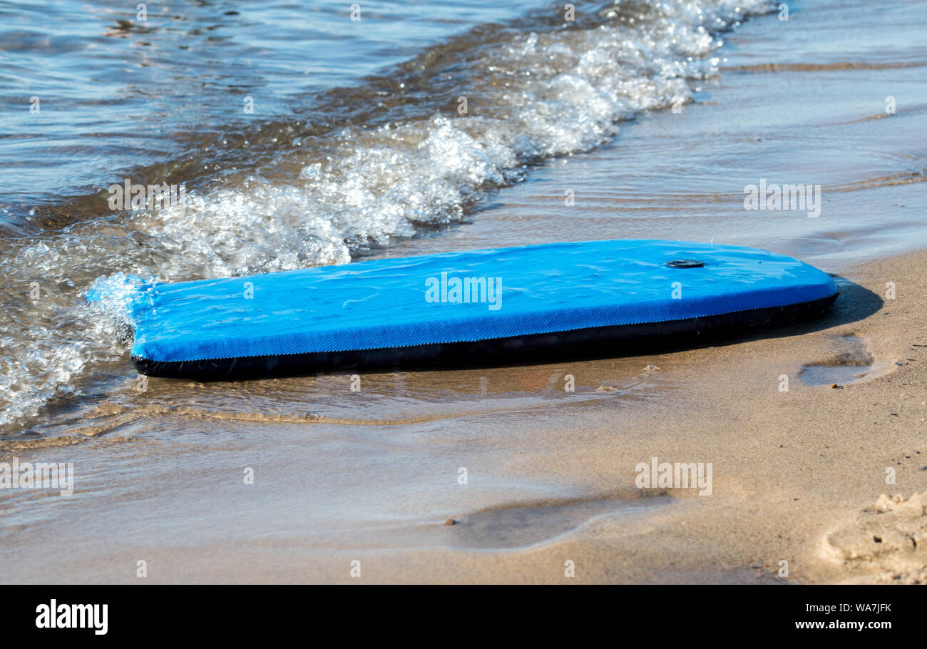 A bright blue beach board washes up on the shore at a beach on Lake Michigan Stock Photo