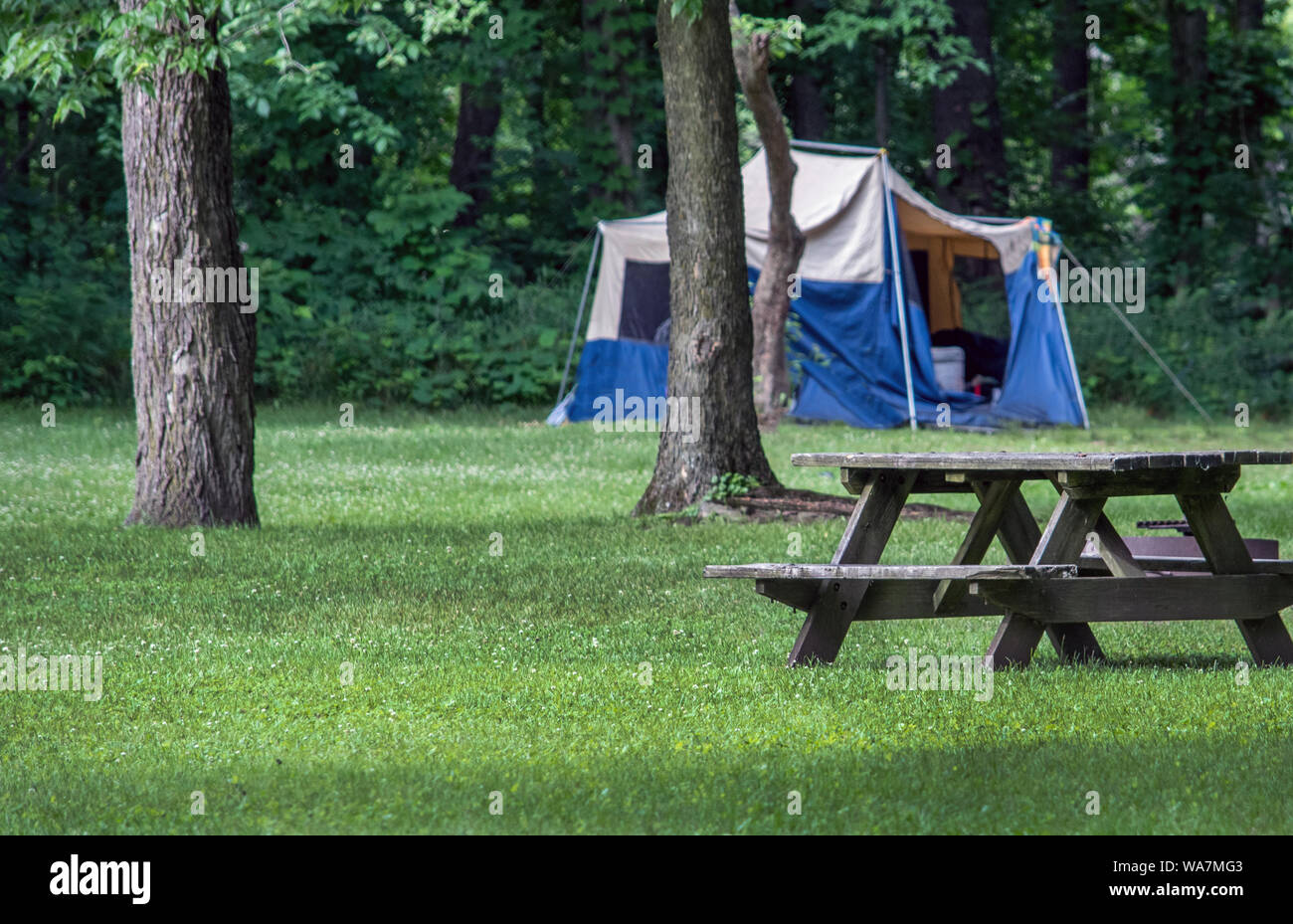 A tent is set up in an Indiana state park, near a picnic table and a grove of trees Stock Photo