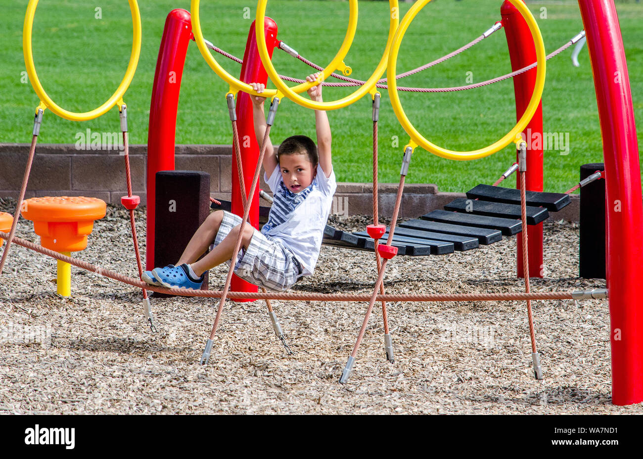 Active little boy playing outdoors on a colorful playground Stock Photo