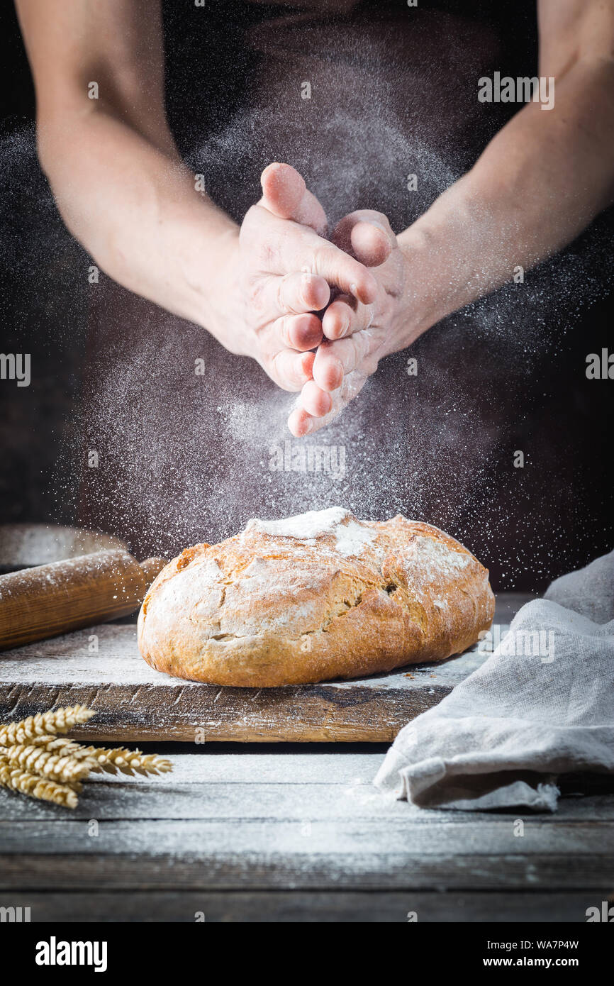 Baker cooking bread. Man slaps flour over the dough. Man's hands Making bread Stock Photo