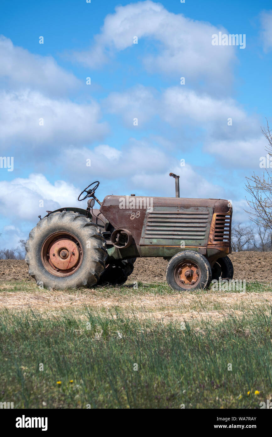 april 28 2018 Buchanan MI USA; very old tractor sitting on a hilltop by a newly plowed field Stock Photo