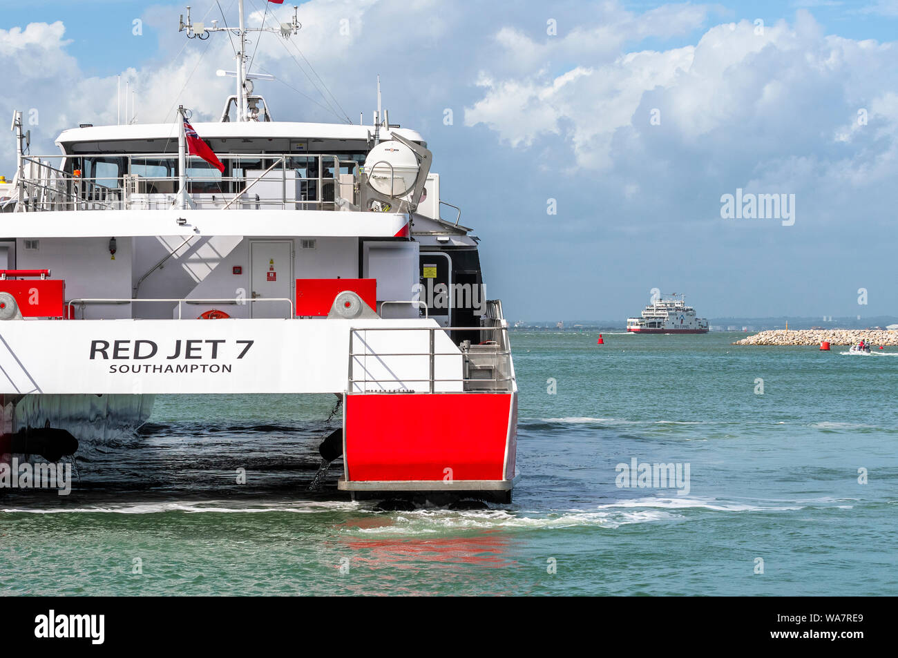 Red Jet 7 leaving West Cowes, Isle of Wight with the vehicle ferry in the distance coming into the harbour from Southampton, Hampshire, England, UK Stock Photo