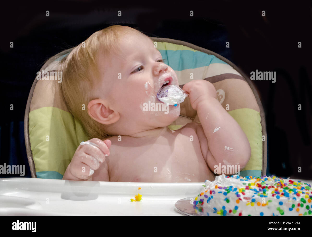 happy baby digs into her first birthday cake Stock Photo