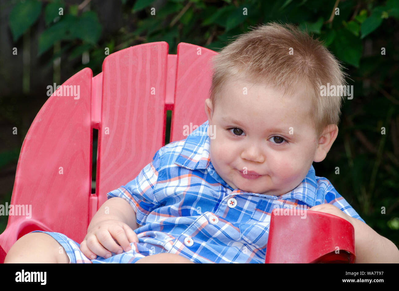 baby boy in a red chair, making a funny face Stock Photo