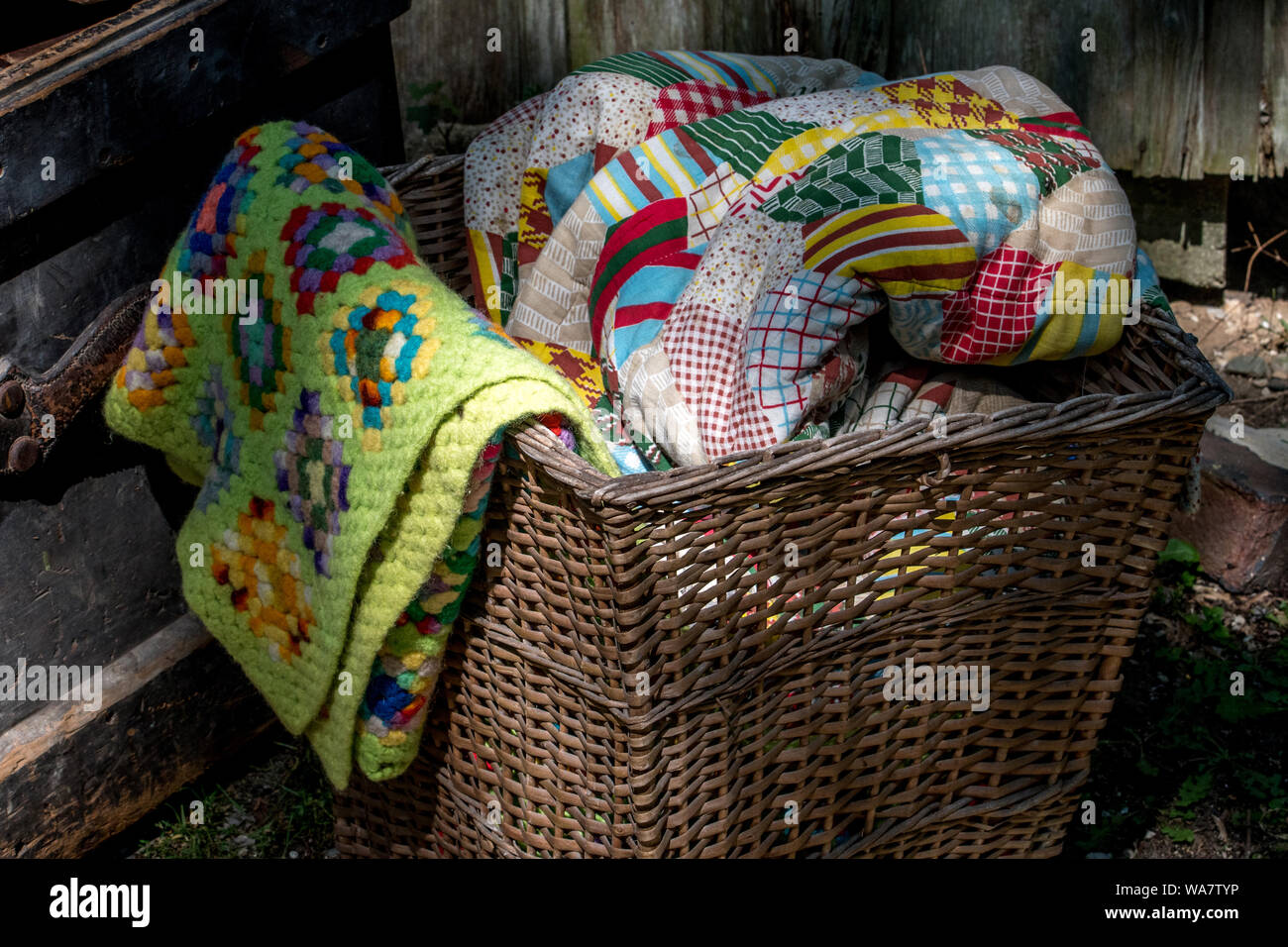 old wicker basket filled with hand made quilts and blankets Stock Photo