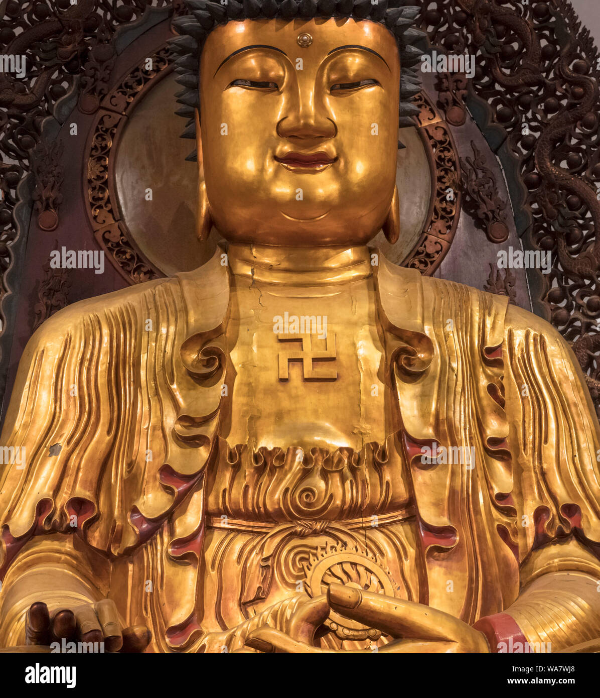 Swastika on the chest of a Buddha statue in the Grand Hall of the Jade Buddha Temple, Shanghai, China. In Buddhism, the swastika is considered to symbolize the auspicious footprints of the Buddha. Stock Photo