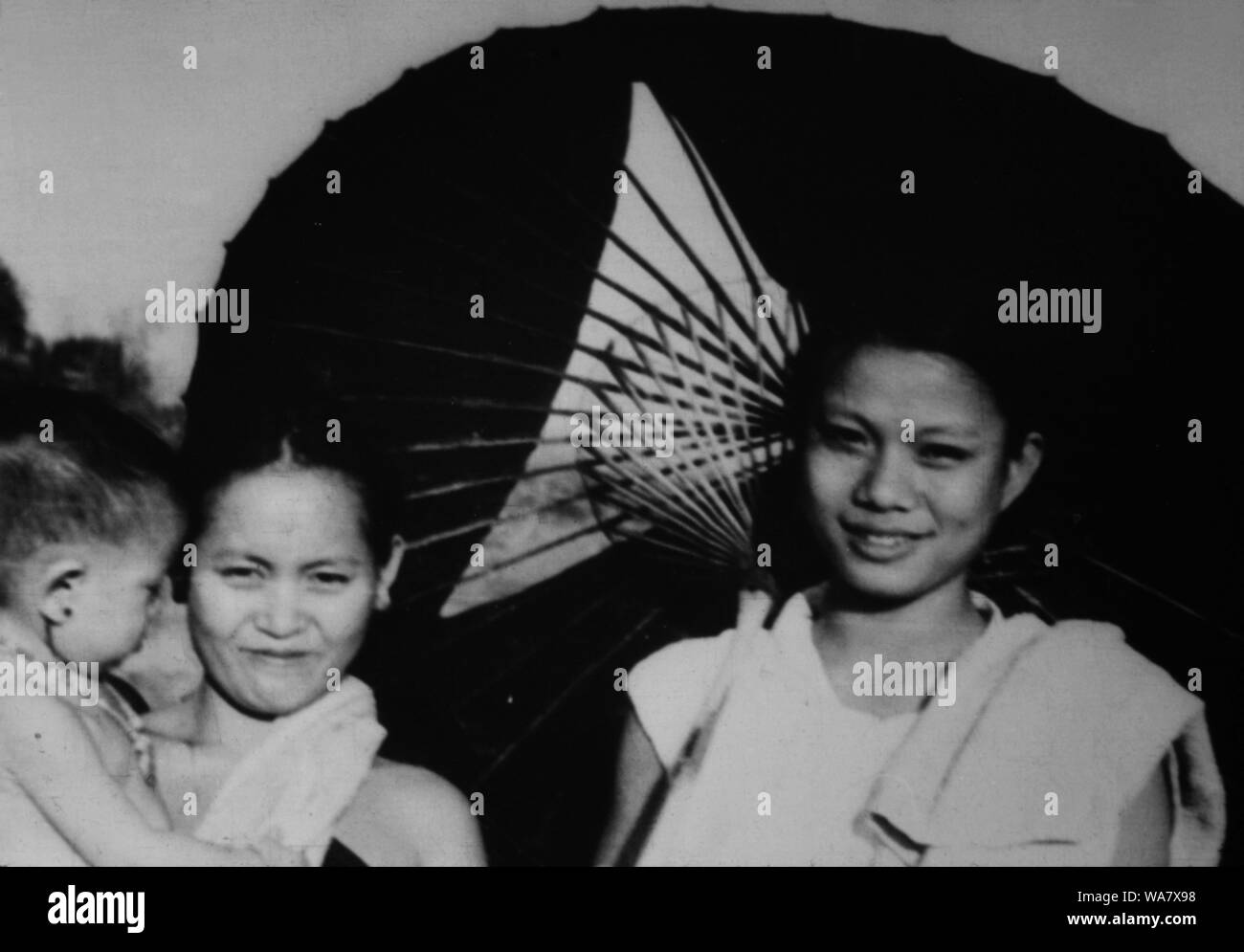 AJAXNETPHOTO. 1953-1957 (APPROX). INDO CHINA. VIETNAM. (IN-COUNTRY LOCATION UNKNOWN.) - TWO WOMEN WITH A CHILD AND TRADITIONAL PARASOL.  PHOTO:JEAN CORRE/AJAXREF:RX7 191508 224 Stock Photo