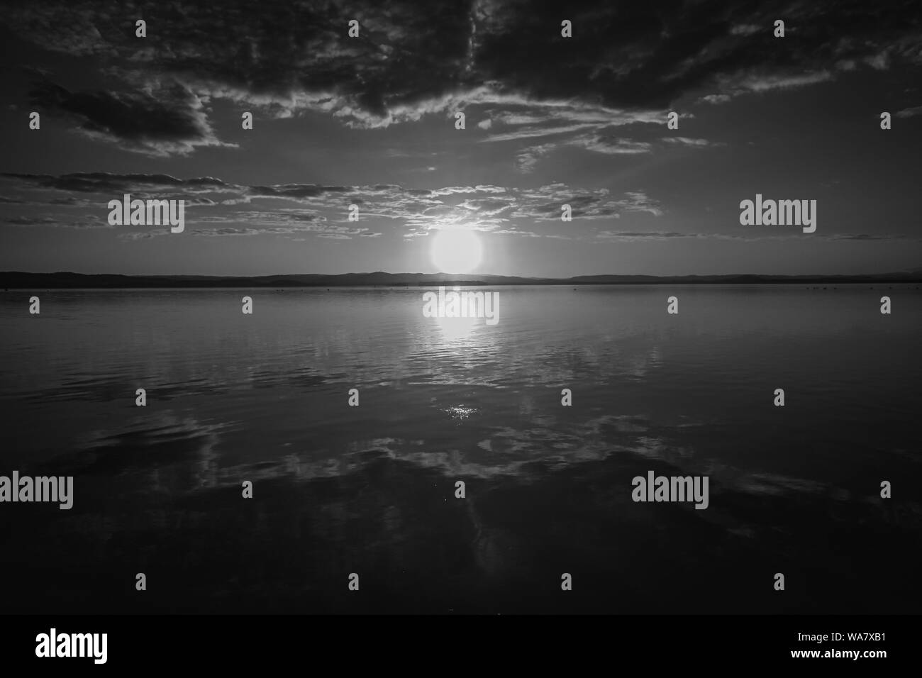 Beautiful scenic view of the red sunset over a lake shot in black and white Stock Photo