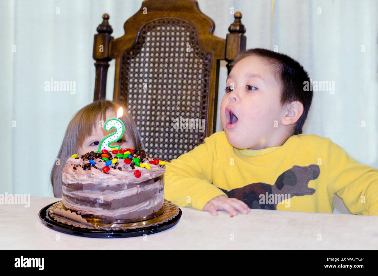 little boy Blowing out candles on his sister’s birthday cake Stock