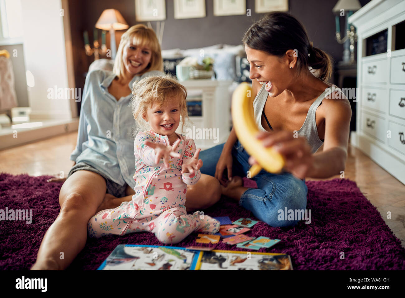 Cute female child gives hand to takes banana Stock Photo