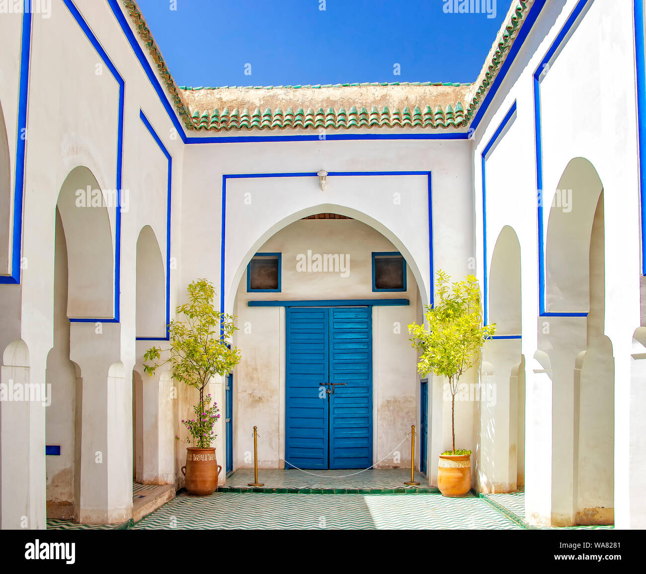 Courtyard at El Bahia Palace, Marrakech, Morocco. there are white walls and columns with blue signs and blue doors. Stock Photo