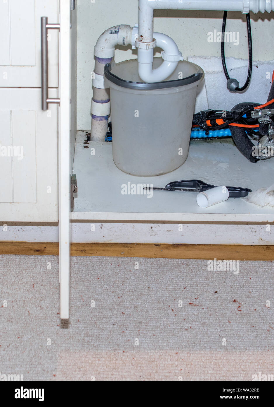 bucket under a pipe of a leaking sink with tools close by to fix it