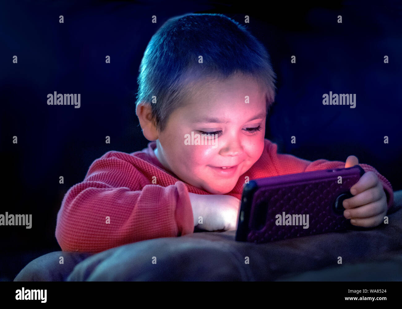 Young child is amused as he watches videos on moms cell phone Stock Photo