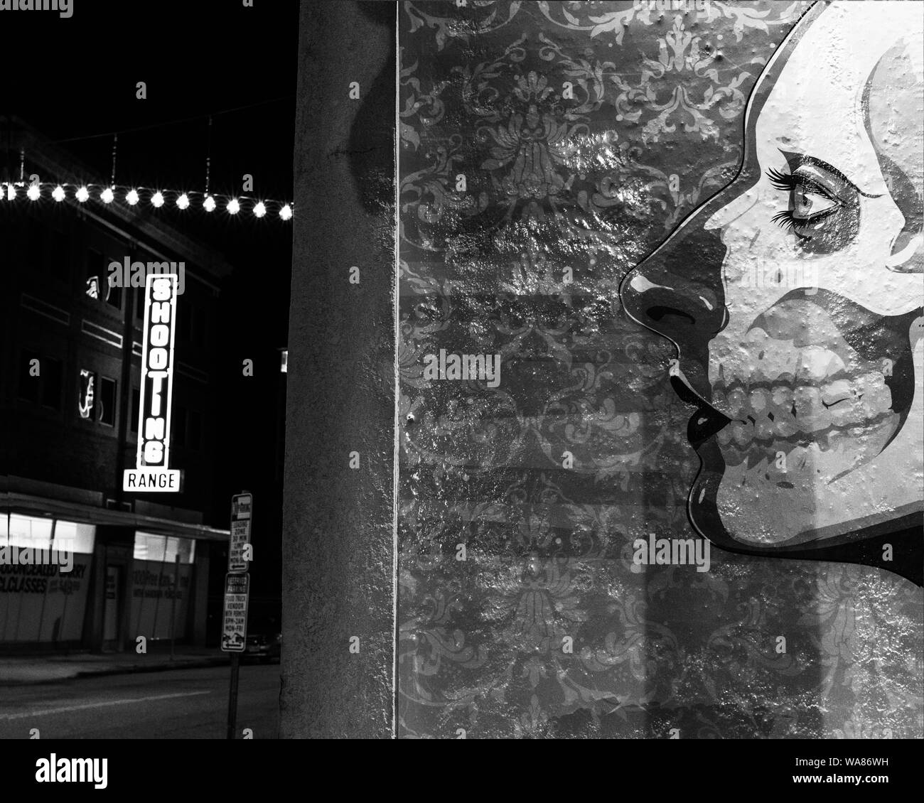A skull mural on a building in Norfolk Virginia with a shooting sign in the background Stock Photo